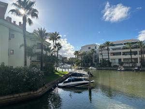 un barco atracado en un canal con palmeras y edificios en Sotogrande apartamento duplex, en Sotogrande