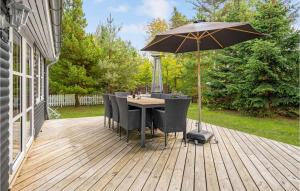 eine Holzterrasse mit Tisch und Sonnenschirm in der Unterkunft Three-Bedroom Holiday Home In Vaggerlose in Bøtø By