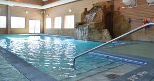 a swimming pool with a waterfall in a building at Crooked River Lodge in Alanson