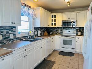 a kitchen with white cabinets and a sink at Beach Ya There in Holden Beach