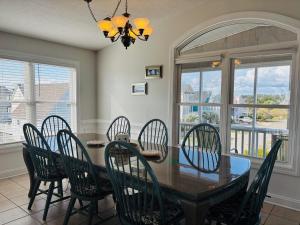 a dining room with a table and chairs and windows at Beach Ya There in Holden Beach +63 photos