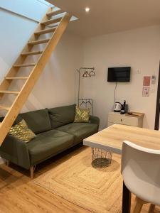 a living room with a green couch and stairs at Hébergement Ornano Bordeaux in Bordeaux