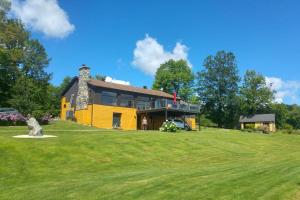 a yellow house on top of a green field at Spacious luxurious Villa, bright cottage, pool, Jacuzzi, sauna, nature in Mansonville