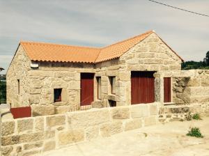 una antigua casa de piedra con techo naranja en Casa de Sao Cosmado, en Mangualde