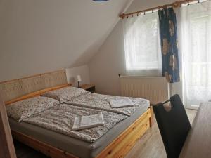 a bedroom with a bed with a wooden frame and windows at Kiss Vendégház in Balatonlelle