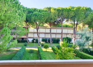 a view of a building with trees and a garden at ISA-Holiday Homes with common swimming-pool in Marina di Bibbona from 400 to 900 meters from the sea in Marina di Bibbona