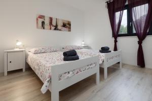 a white bedroom with two beds and two windows at Villa Marconi in Potpićan +34 photos