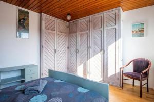 una camera con letto, sedia e armadio di Maison à l'orée du BOIS CITADELLE de LILLE avec TERRASSE en plein sud PROCHE DE TOUTES COMMODITES à la porte de LILLE a Lambersart