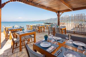a restaurant on the beach with tables and chairs at Roda Beach Resort & Spa in Karousádes