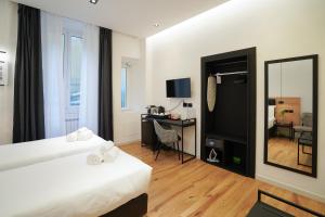 a hotel room with two beds and a desk and a mirror at No Man's Land Guesthouse in Rome