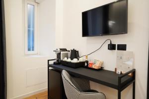 a black desk with a chair and a television on a wall at No Man's Land Guesthouse in Rome