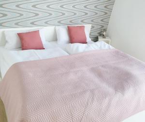 a bedroom with a white bed with two pink pillows at schwimmende Ferienwohnung Sundowner in Elsterheide