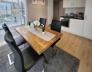 a dining room table with black chairs and a kitchen at schwimmende Ferienwohnung Sundowner in Elsterheide