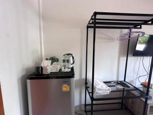 a small refrigerator in a room with a shelf at นิวเวฟภูเก็ต in Ban Na Kok