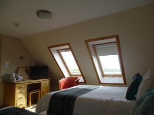 a bedroom with two beds and a desk and two windows at The Sands Hotel in Orkney