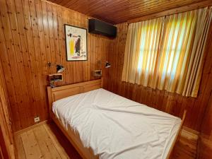 a small bedroom with a bed in a wooden room at Pré Vert in Durbuy