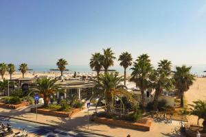 Blick auf einen Strand mit Palmen und ein Gebäude in der Unterkunft Appartamento Bellariva D2 - MyHo Casa in Porto San Giorgio