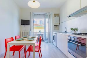 eine Küche mit einem weißen Tisch und roten Stühlen in der Unterkunft Appartamento Bellariva D2 - MyHo Casa in Porto San Giorgio + 9 Fotos
