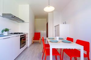 eine Küche mit einem weißen Tisch und roten Stühlen in der Unterkunft Appartamento Bellariva D2 - MyHo Casa in Porto San Giorgio