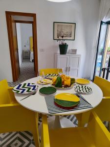 een witte tafel met gele stoelen en een bord met eten erop bij Case Borgo Vacanze in Letojanni