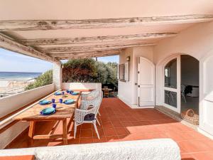 a patio with a wooden table and chairs and the ocean at Villa Adea in Santa Teresa Gallura