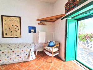 a bedroom with a bed and a chair and a window at Small cozy house Susana in Mogán