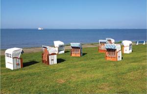 un groupe de chaises assises sur l'herbe près de l'océan dans l'établissement Amazing Home In Dagebüll With Sauna, à Dagebüll
