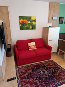 a red couch in a living room with a rug at Ferienwohnungen Oliver Bayer in Bad Schallerbach