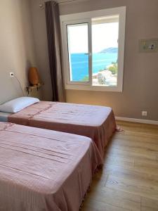 two beds in a room with a large window at El Valles Apartment sea view in Llança