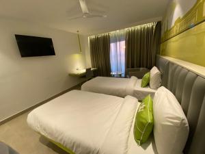 a hotel room with two beds and a television at Le Roi Dehradun at Dehradun Railway Station in Dehradun
