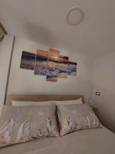 a bedroom with a bed with four paintings on the wall at Tarantè Apartment in Naples