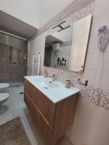a bathroom with a sink and a toilet and a mirror at Tarantè Apartment in Naples