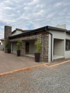 a building with two potted plants in front of it at Kioma Guest House in Mokopane