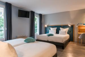 a hotel room with two beds and a tv at Hôtel Sanso by HappyCulture in Paris