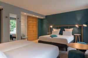 a hotel room with two beds and a table at Hôtel Sanso by HappyCulture in Paris