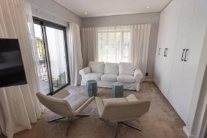 a living room with two chairs and a couch and a tv at Waveren's Nest in Cape Town