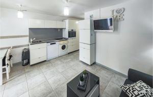 una pequeña cocina con armarios blancos y una mesa en 2 Bedroom Awesome Home In Marseillan, en Marseillan