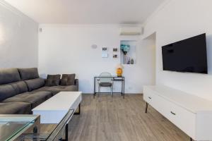 Una sala de estar con un sofá y un televisor de pantalla plana. en Increíble terraza vista al mar, wifi y parking, en Torremolinos
