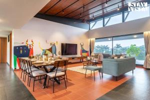 Un comedor con mesa y sillas y un televisor. en StayVista at Kai By The Lake with Pool, en Nashik