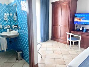 a blue tiled bathroom with a sink and a desk at Best Western Hotel Blumarea in Castelsardo