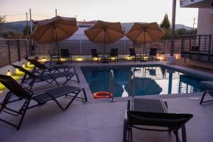 a swimming pool with chairs and umbrellas next to a pool at SanGerasimo Villas in Melíssion