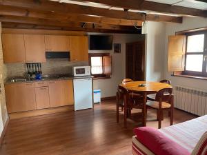 a kitchen with a table and a dining room at Apartamentos el Cueto de los Collado in Villanueva de Pría