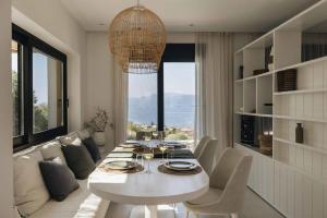 a white dining room with a table and a couch at Villa No Worries - Where Tranquility meets Luxury in Paleros