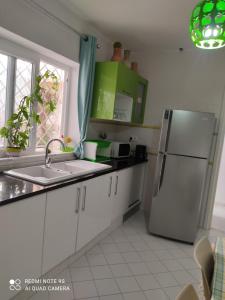 a kitchen with a refrigerator and a sink at Villa Chic Garden & Parking -10 mn Airport in Ariana