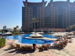 a swimming pool with chairs and umbrellas and buildings at Frank Porter - Diamond, Tiara Residences in Dubai