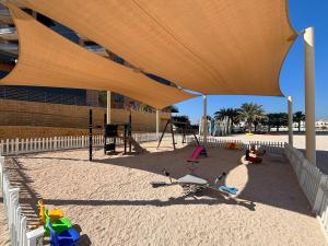 a play area with a playground with a large umbrella at Frank Porter - Diamond, Tiara Residences in Dubai
