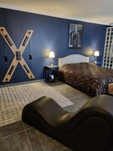 a bedroom with a king sized bed and a black chair at Love Room La Volupté Spa Privatif in Bétheniville
