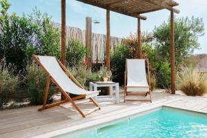 a pair of chairs sitting on a deck next to a pool at Casa Azul Comporta in Comporta