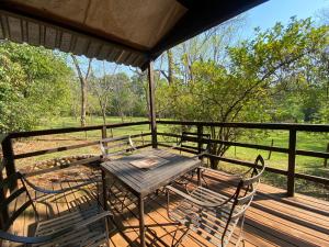 a table and chairs on a porch with a view of a field at Buhleni Farm Chalets in Ezulwini