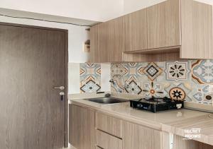 Una cocina con gabinetes de madera y fregadero y azulejos. en The Jarrdin Apartement by Secret Rooms, en Bandung